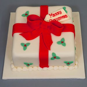 Premium Vector | A christmas cake with a red christmas present on top of it.